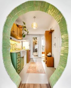 an oval view of a kitchen with green and white tiles on the walls, along with hardwood floors