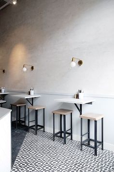 an empty restaurant with white tables and stools