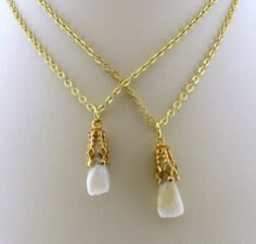 two pieces of gold chain with white glass pendants