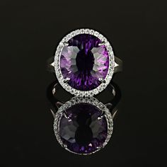 This is part of Chairish’s Fine Jewelry assortment.  Elegant Evening Cocktail Ring of oval Amethyst, 12.40ct, surrounded by sparkling genuine zircons, 0.57ct.  This unique amethyst is a special cut with extra sparkle and flashes of pink in the purple.  The setting is sterling silver featuring a lovely lattice design. Amethyst is the February birthstone and is said to protect from intoxication and evil spells. It will calm your spirit and give you focus. Pure quartz is colorless, but the most pri Oval Diamond Gemstones With Accents, Oval Gemstones With Diamond Accents Luxury Style, Luxury Purple Gemstones With Halo Setting, Oval Cubic Zirconia Ring With Gemstone Accents, Oval Cubic Zirconia Diamond Ring With Gemstone Accents, Oval Diamond Ring With Cubic Zirconia And Gemstone Accents, Formal Halo Diamond Amethyst Ring, Luxury Oval Gemstones With Halo Setting, Formal Purple Halo Rings