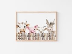 three farm animals are hanging on the wall behind a wooden fence, and one is looking at the camera