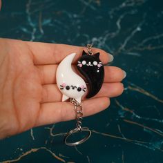 a hand holding a black and white cat keychain