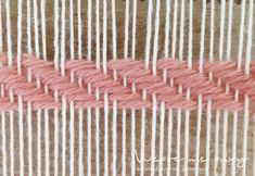 pink and white yarn is being woven on a loom