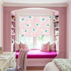 a bedroom with pink walls and built - in bookshelves has a window seat