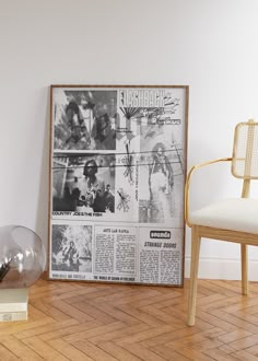 an old newspaper is sitting on the floor next to a chair and a glass vase