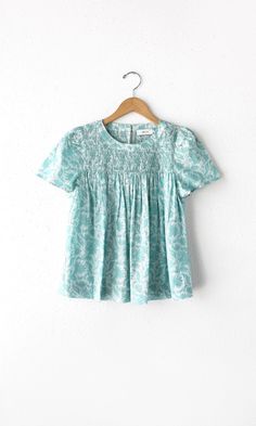 An easy-to-wear blouse for a casual setting. Features smocking, short sleeves, and mint pattern print. Style with jeans or any other bottoms to change the mood. Short sleeves Mint color Self: 100% Cotton Length: 23 1/2" Chest: 18 3/4" Hand wash in cold water. Lay flat to dry. Low iron. Model is wearing a size small Style #: G242T6979 Vacation Smocked Top With Short Sleeves, White Smocked Top With Floral Print And Short Sleeves, White Floral Print Smocked Top With Short Sleeves, White Smocked Short Sleeve Top, Green Summer Blouse With Smocked Cuffs, White Short Sleeve Smocked Top With Floral Print, White Smocked Top With Short Sleeves, Summer Green Blouse With Smocked Cuffs, Summer Tops With Smocked Back And Short Sleeves