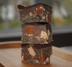 three pieces of chocolate sitting on top of a wooden table next to a window with sunlight coming in