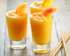 two glasses filled with orange juice on top of a wooden table