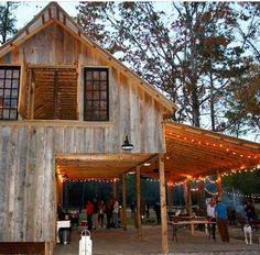 people are standing outside in front of a wooden building with lights on the roof and windows