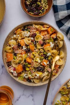 a bowl filled with pasta and vegetables next to other dishes on a white counter top