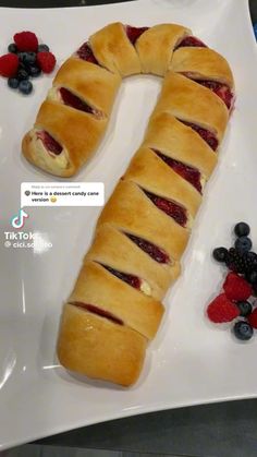 a long piece of bread sitting on top of a white plate next to berries and raspberries