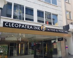 the front entrance to a tattoo and piercing shop in an urban area with lots of windows