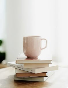 a stack of books with a coffee cup on top