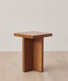 a small wooden table sitting on top of a hard wood floor next to a white wall