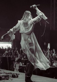 a woman in a long dress is performing on stage