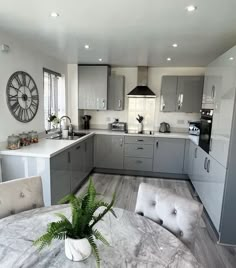 a kitchen with grey cabinets and white counter tops, an oven, sink, microwave, dishwasher, and potted plant on the table