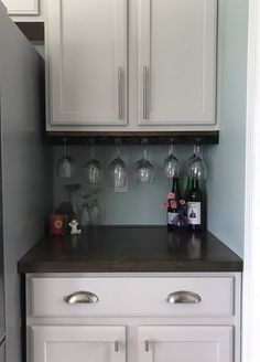 a kitchen with white cabinets and wine glasses on the counter