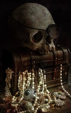 a skull sitting on top of a chest filled with jewelry