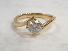 a yellow gold ring with a diamond in the center on a white surface, close up