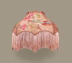 an umbrella with pink flowers and fringes on the top is hanging from a wall