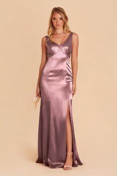 a woman wearing a long purple dress with a slit down the side and one leg