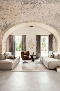 a living room with two couches and a coffee table in front of an arched doorway