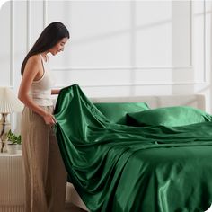 a woman is unwraping a green sheet on a bed in her living room