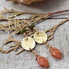 You can almost smell the crisp fall air with these boho autumn earrings. dainty brass disc's are hammered to perfection and adorned with rich green Czech glass and pumpkin orange fall leaves. Finished with 14k gold plated earring hooks. - Gorgeous boho autumn styling - Brass materials - Czech glass beads - 14k gold plated earring hooks with rubber backs included True Autumn Jewelry, Earthy Brass Jewelry With Ear Wire, Earthy Brass Dangle Earrings, Bohemian Leaf-shaped Brass Jewelry, Bohemian Brass Leaf Jewelry, Earthy Nickel-free Brass Jewelry, Rustic Gold Dangle Jewelry, Rustic Brass Dangle Earrings, Rustic Brass Earrings For Gift