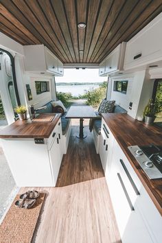 the interior of a camper with wood flooring and white cabinets is shown in this photo