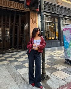 a woman standing next to a traffic light on the side of a road in front of a building