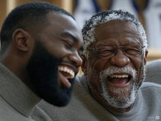 two men laughing while sitting next to each other