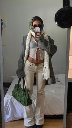 a woman taking a selfie in front of a mirror while holding a green purse