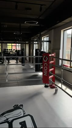 an empty gym with boxing gloves on the floor and punching bags in the background,