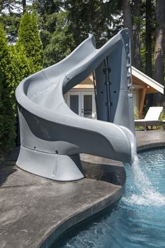 a water slide sitting in the middle of a swimming pool next to a tree filled forest