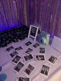 a table topped with pictures and a camera next to a purple wall covered in sequins