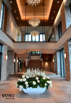 a large white vase filled with flowers on top of a floor next to a staircase