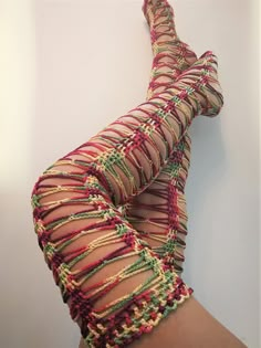 a woman's legs with colorful crochet stockings on them and one leg in the air