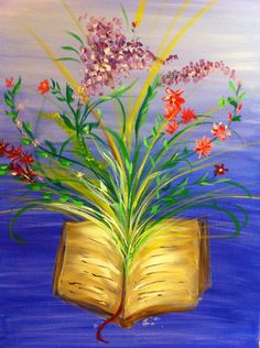 an open book with flowers in it sitting on top of a blue table next to the ocean