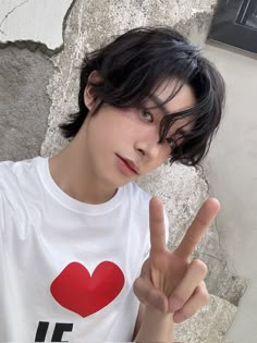 a young man making the peace sign with his hand while standing in front of a stone wall