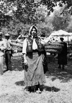 an old black and white photo of a woman standing in front of tents with people around her