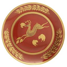 a red and gold plate with an image of a bird on it