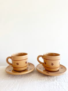 two cups and saucers sitting on top of a table