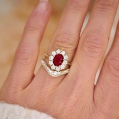 a woman's hand with a diamond and red stone ring on top of it