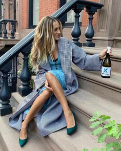 a woman sitting on the steps with a bottle of wine