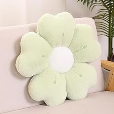 a flower shaped pillow sitting on top of a couch next to a potted plant