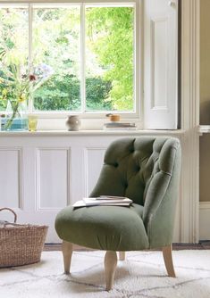 a green chair sitting in front of a window next to a basket and flower pot