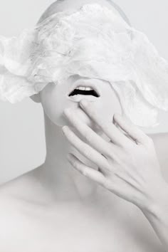 a woman covered in white paper covering her face and hands with one hand on the other side of her face