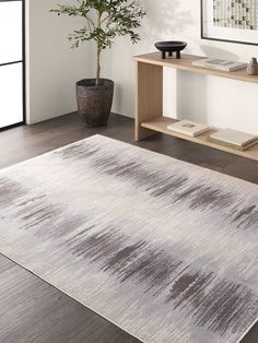 a white and gray area rug in a living room with a potted plant next to it