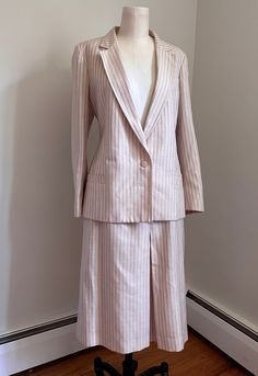 "This listing is for BOTH the skirt and the blazer.  This is such a classic, never out of style suit set by Saks Fifth Avenue! Made in the 1970's, this gorgeous suit includes a pencil skirt and a single button blazer. The suit is a gorgeous cream color with pink pin stripes, a subtle pop of color. I love the suit together but it also looks great separated, just the skirt or just the blazer!  Saks Fifth Avenue label, suit is a silk/poly/rayon blend. Luxurious feeling suit. Light shoulder pads, fr Spring Retro Blazer For Tailoring, Retro Fitted Suits For Spring, Retro Fitted Spring Suits, Spring Retro Fitted Suits, Vintage Tailored Blazer For Spring, Vintage Lined Skirt Suit For Formal Occasions, Classic Notch Lapel Skirt Suit For Spring, Vintage Semi-formal Spring Suits, Retro Long Sleeve Skirt Suit For Tailoring