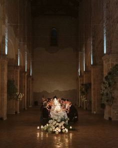 a group of people sitting at a table with candles on it in an old building